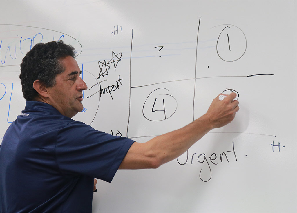 an image of a teacher writing on a white board in a classroom setting